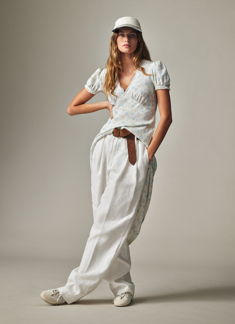 Woman wears white button-down and white frayed shorts.