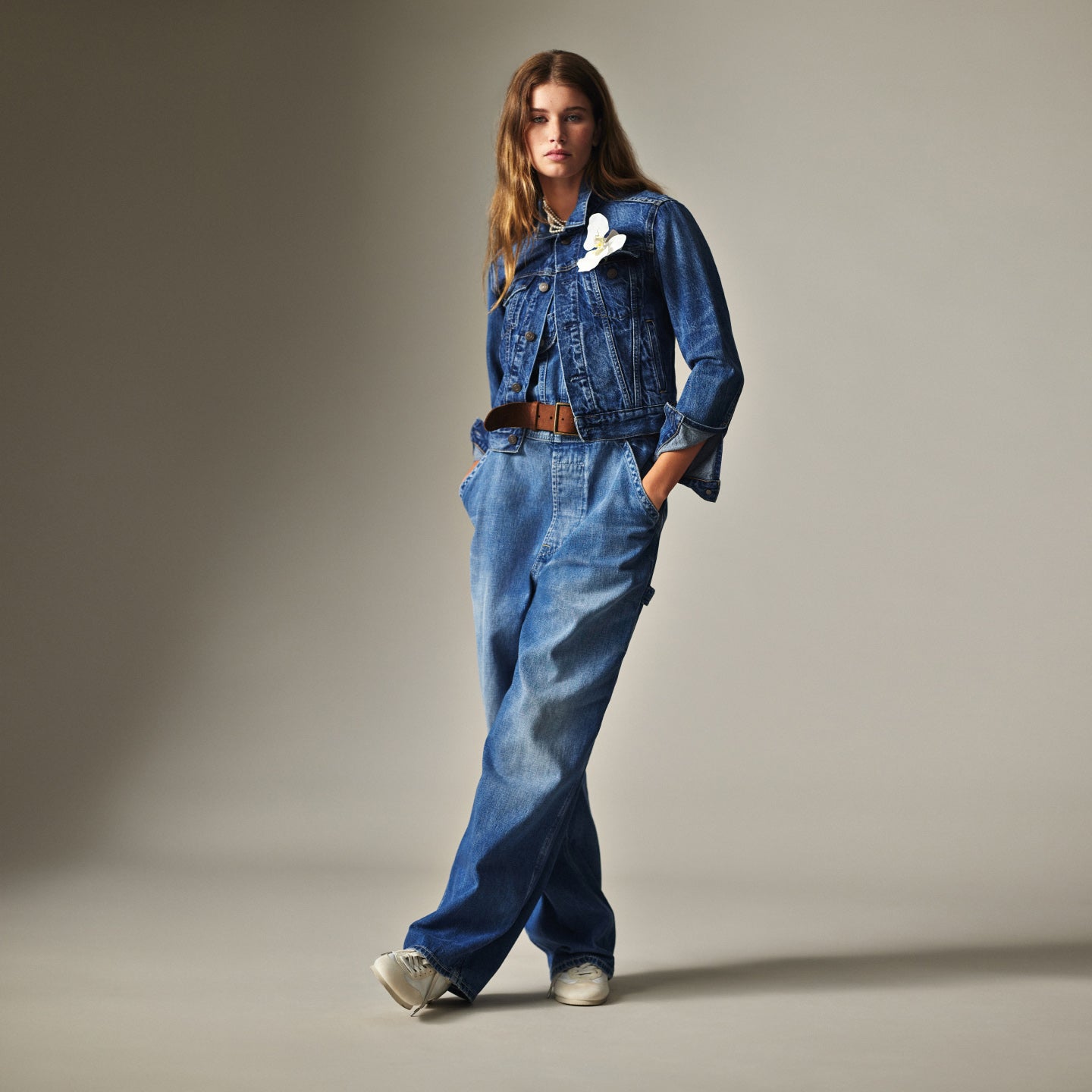 Woman wears denim trucker jacket and wide-leg jeans.