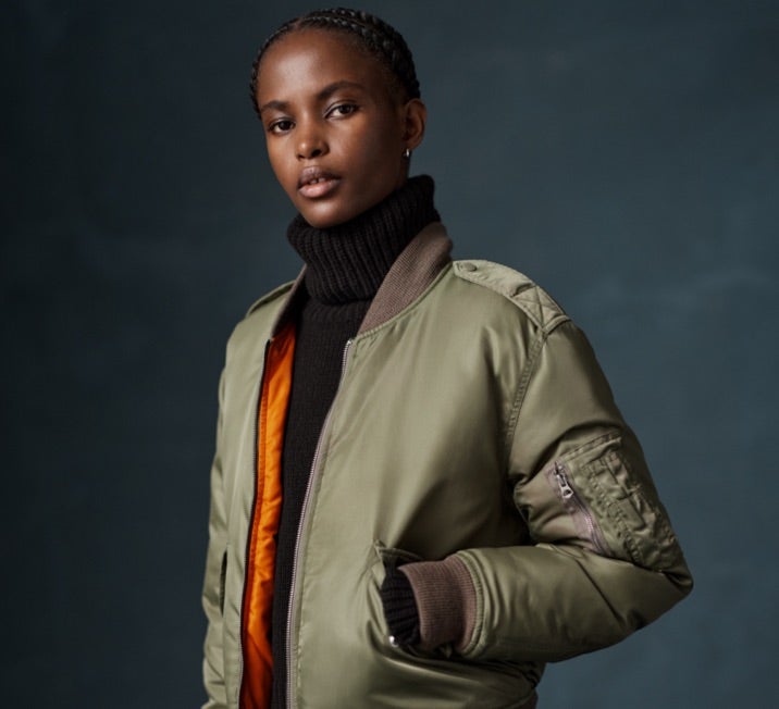 Woman wears green down-filled bomber jacket.