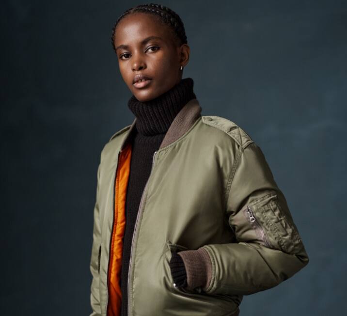 Woman wears green down-filled bomber jacket.
