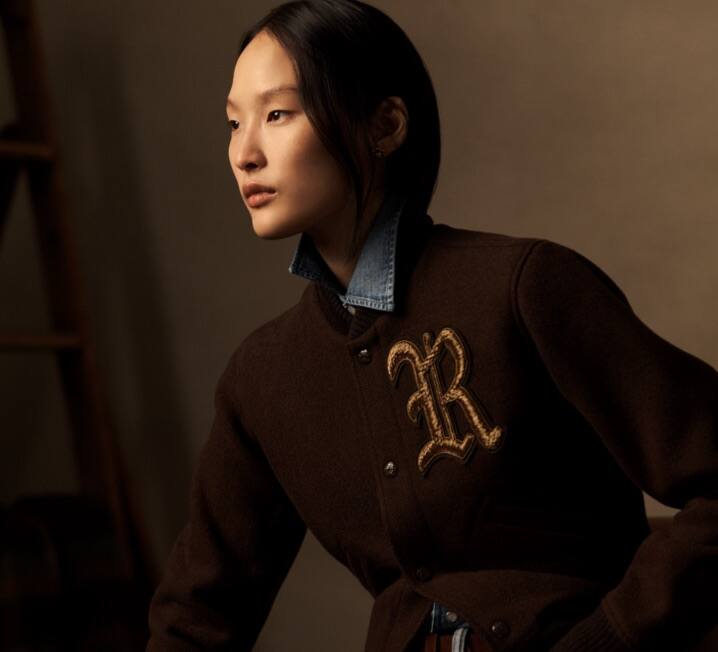 Woman wears camel wool coat over grey turtleneck.